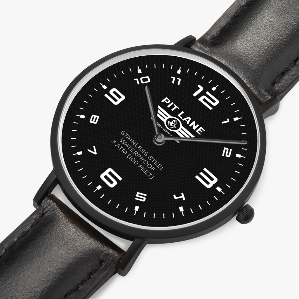 A Pit Lane Clothing analog wristwatch with a black leather strap, black dial, and silver-tone case, centered against a light gray textured background.