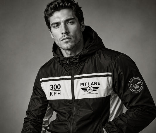 A man wearing a black and white Pit Lane Clothing hooded jacket, photographed in black and white against a neutral studio background.