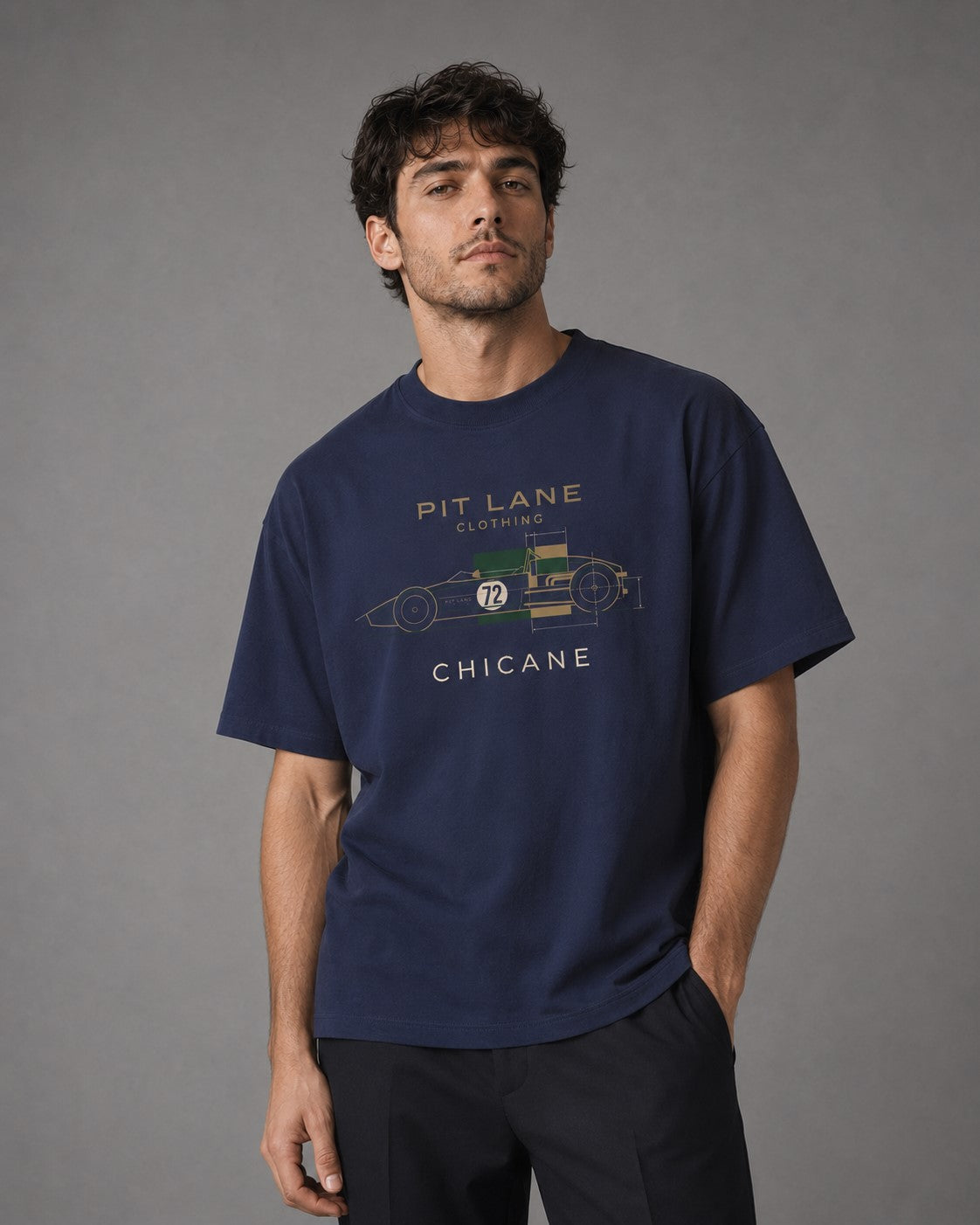 A man wearing a navy blue graphic t-shirt with a vintage race car design and 'PIT LANE CLOTHING' text, posed against a neutral gray studio background.