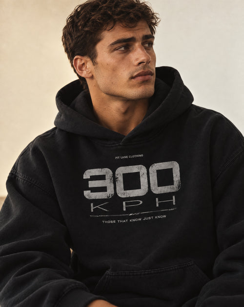 A black pullover PIT LANE CLOTHING hoodie with a distressed white graphic on the chest reading '300 KPH' and smaller text above and below, shown on a plain white background.