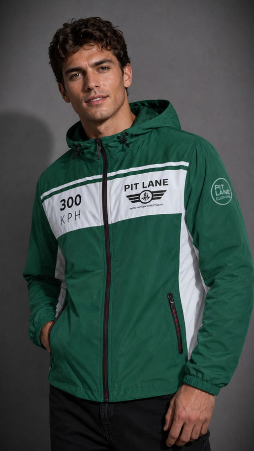 A man wearing a green and white hooded windbreaker jacket with 'PIT LANE CLOTHING' and '300 KPH' graphics, posed against a dark gray studio background.