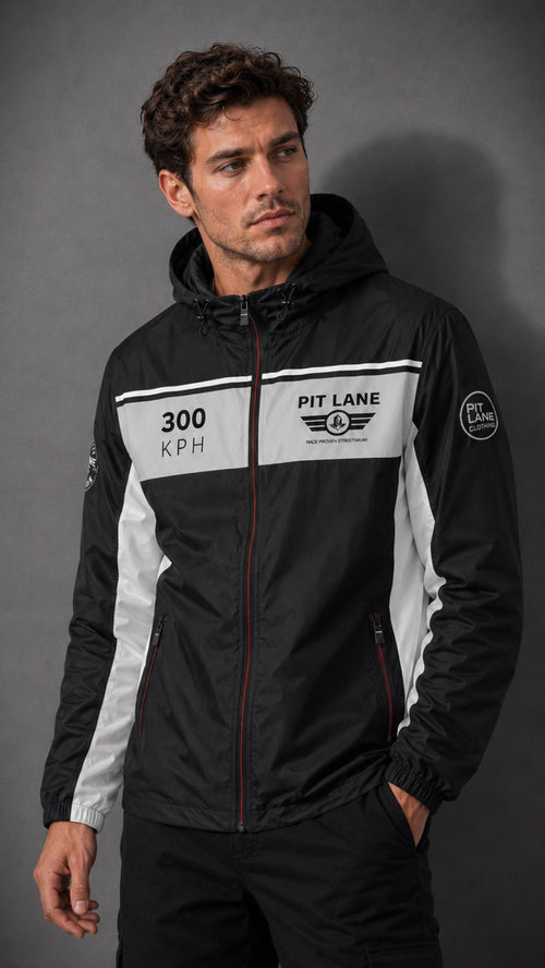 A man wearing a black and white hooded jacket with 'PIT LANE CLOTHING' and '300 KPH' graphics on the chest, posed against a dark gray studio background.
