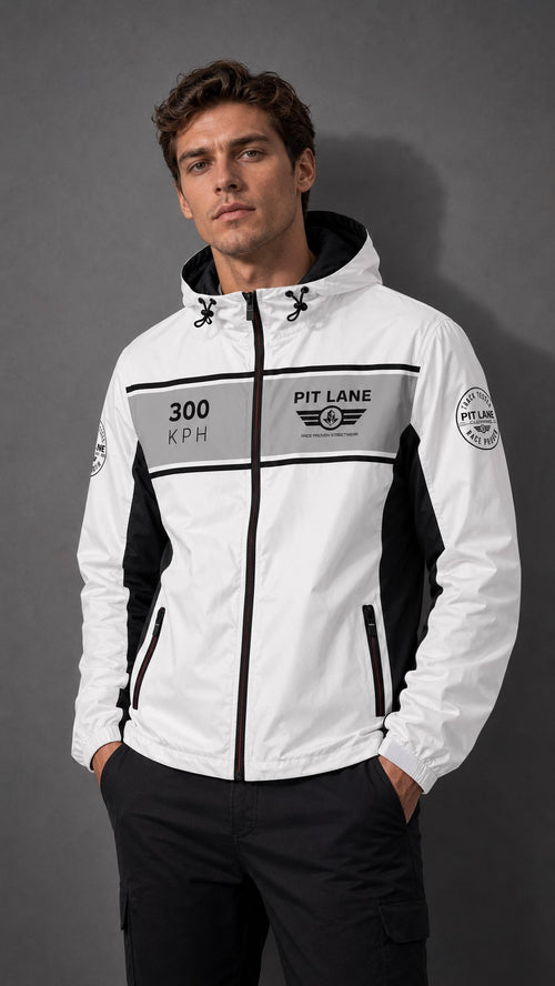 A man wearing a white and black hooded jacket with 'PIT LANE' and '300 KPH' graphics, posed against a dark gray studio background.