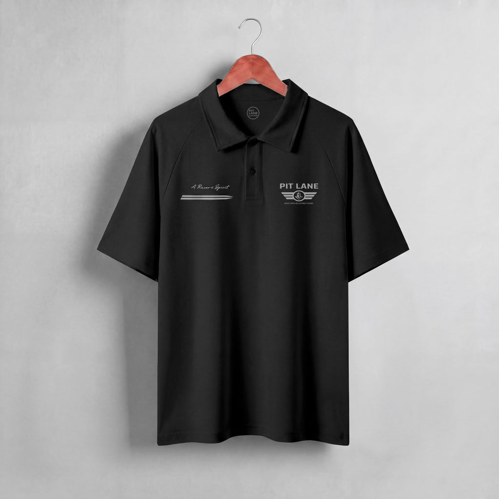 A dark navy blue short-sleeve polo shirt hanging on a wooden hanger against a light gray textured wall. The shirt features white embroidered graphics on the chest, including 'PIT LANE' with wings on the left chest and a script logo on the right chest.