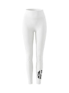 A woman modeling white athletic leggings with a black 'PIT LANE' logo on the lower left leg, paired with a dark gray long-sleeve athletic top and black sneakers, against a gray studio background.