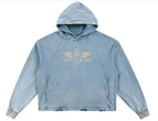 A light blue acid-wash cropped hoodie with a distressed gold 'PIT LANE' graphic printed on the chest, displayed against a solid white background.