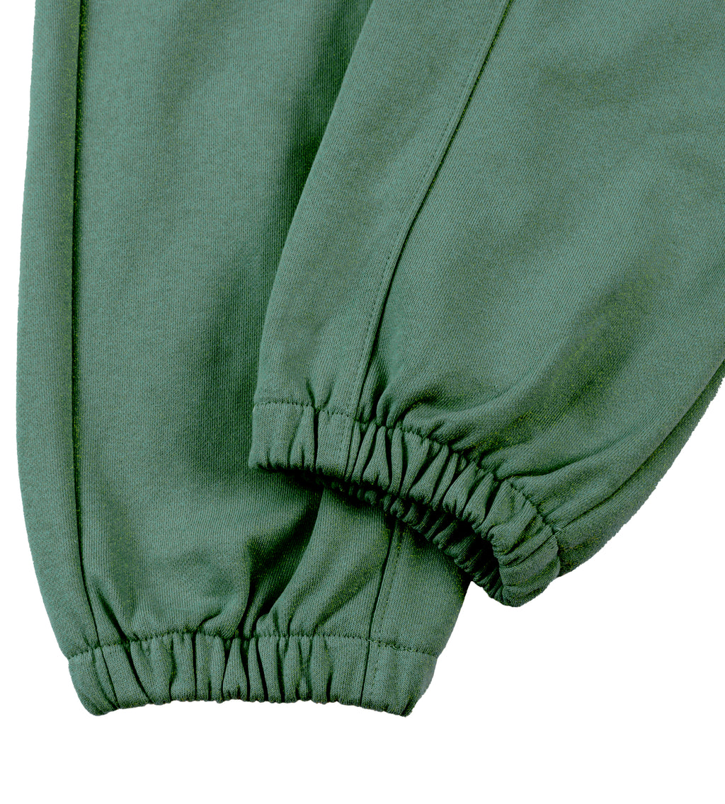 Close-up detail of a pair of jogger sweatpants in a muted sage green color, showing the elasticized ankle cuffs.