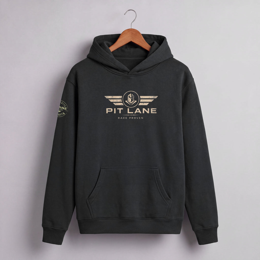 A dark charcoal gray pullover hoodie hanging on a wooden hanger against a light gray wall. The hoodie features a distressed gold graphic on the chest with the text 'PIT LANE' and 'RACE PROVEN' beneath it, and a matching circular graphic on the left sleeve.