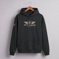 A dark charcoal gray pullover hoodie hanging on a wooden hanger against a light gray wall. The hoodie features a distressed gold graphic on the chest with the text 'PIT LANE' and 'RACE PROVEN' beneath it, and a matching circular graphic on the left sleeve.