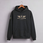 A dark charcoal gray pullover hoodie hanging on a wooden hanger against a light gray wall. The hoodie features a distressed gold graphic on the chest with the text 'PIT LANE' and 'RACE PROVEN' beneath it, and a matching circular graphic on the left sleeve.
