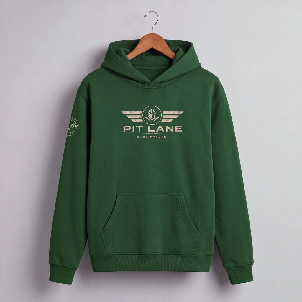 A dark green pullover hoodie hanging on a wooden hanger against a light gray wall. The hoodie features a beige graphic on the chest with the text 'PIT LANE' and 'RACE PROVEN' beneath it, and a matching graphic on the left sleeve.