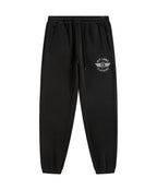 Black sweatpants with an elastic waistband, drawstring, side pockets, and a white circular winged logo on the left thigh that reads 'PIT LANE CLOTHING' graphic on the left thigh.