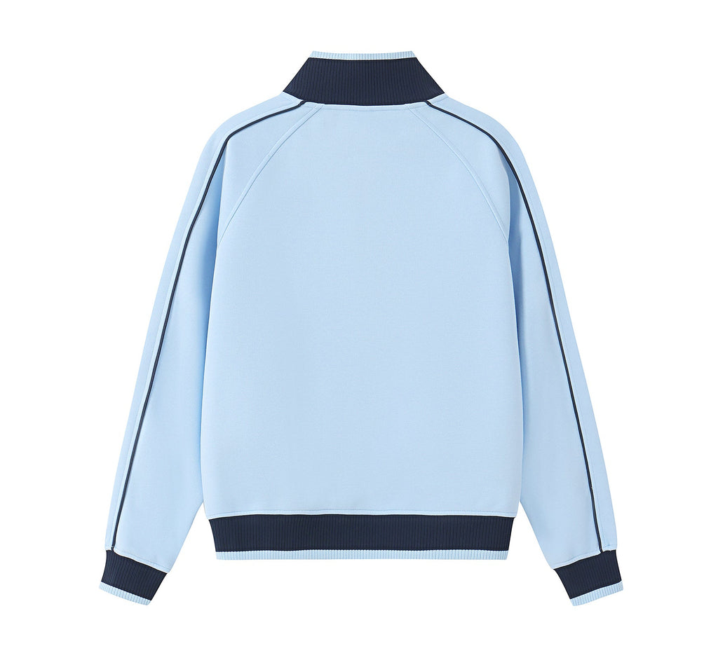 A close-up of a light blue zip-up jacket with a dark navy ribbed collar and a black 'PIT LANE CLOTHING' logo printed on the chest.
