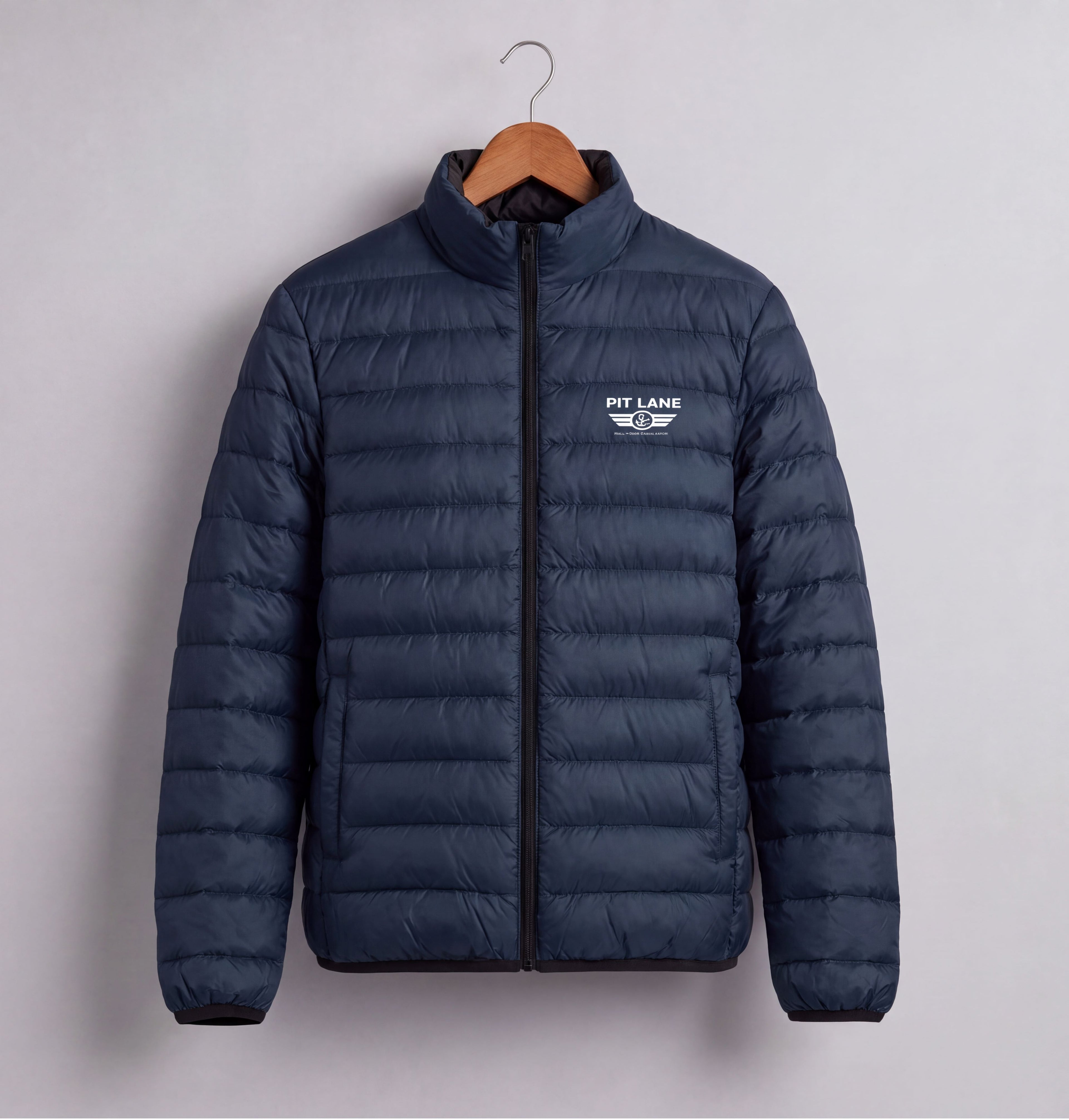 A navy blue puffer jacket with a black front zipper and a white 'PIT LANE' logo on the left chest, hanging on a wooden hanger against a light gray background.