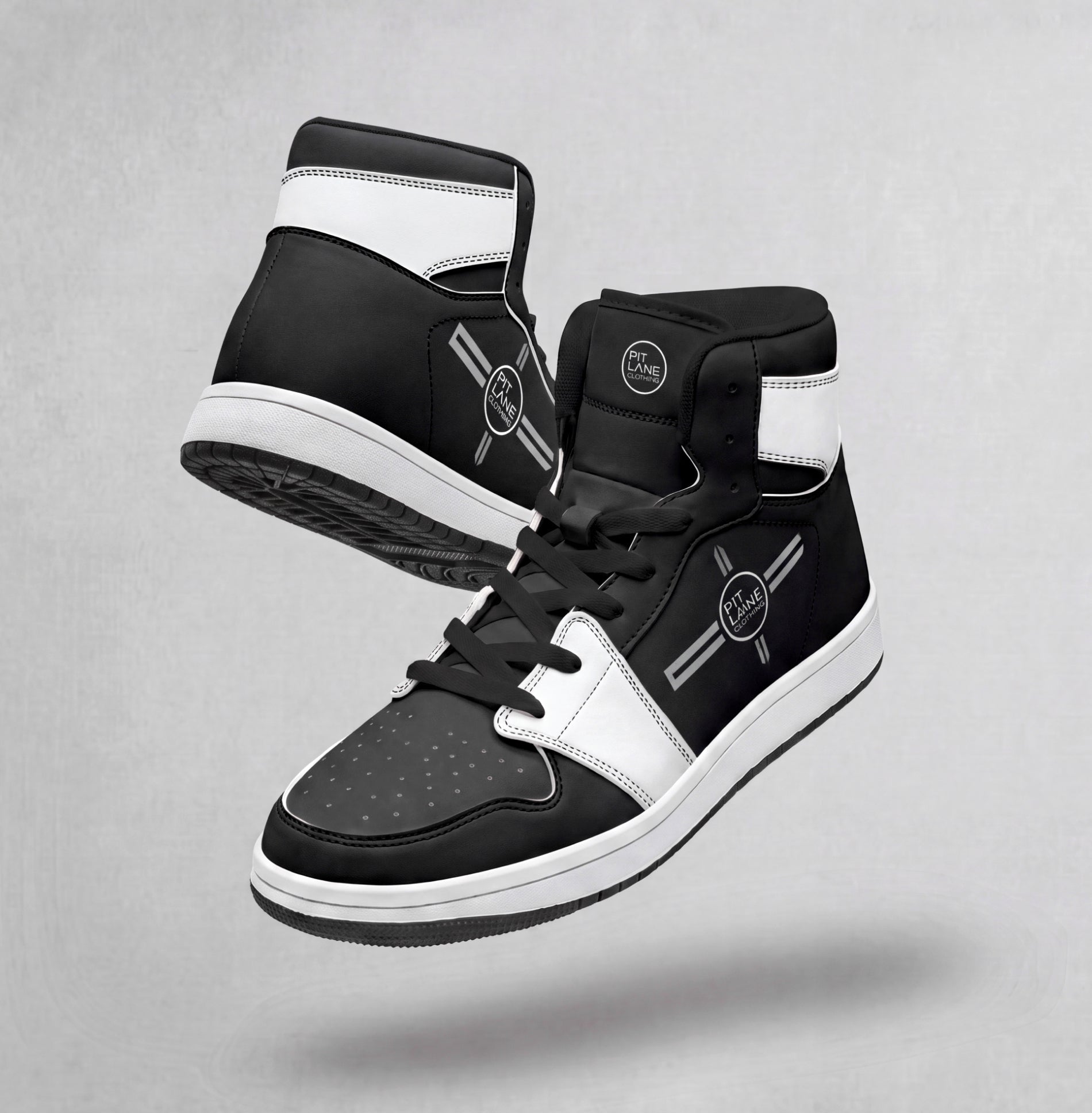 A pair of black and white PIT LANEC LOTHING high-top sneakers floating against a textured gray background. The sneakers feature a black leather upper with white panels, black laces, and a white midsole.