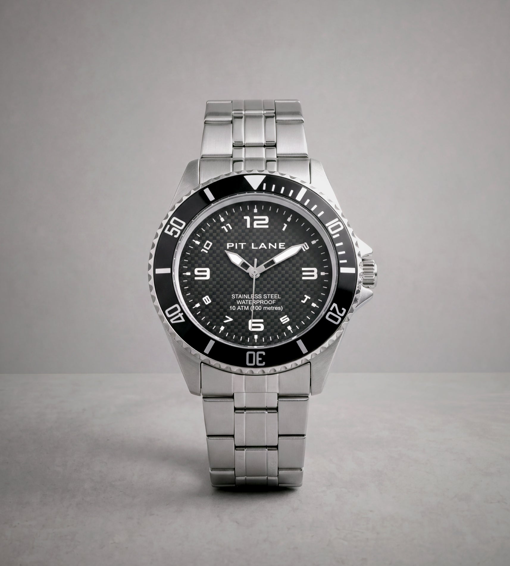 A Pit Lane Clothing stainless steel wristwatch with a black dial and bezel, featuring silver-tone metal case and link bracelet, photographed against a neutral gray background.