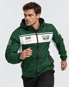 A man wearing a green and white PIT LANE CLOTHING windbreaker jacket, posed in a running stance against a light gray studio background.