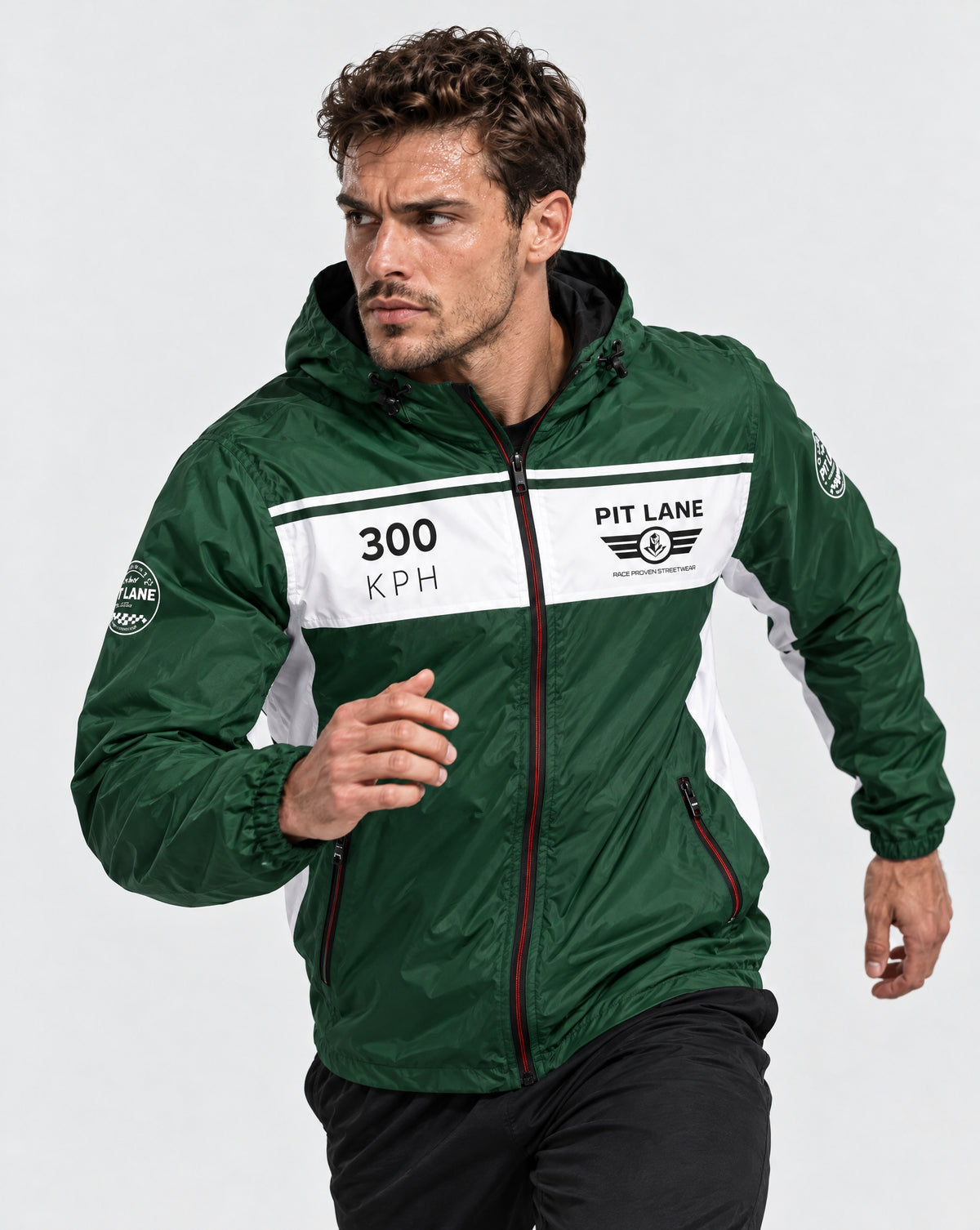 A man wearing a green and white PIT LANE CLOTHING windbreaker jacket, posed in a running stance against a light gray studio background.