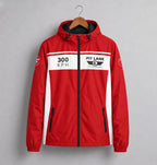 A red hooded jacket with white side panels and a black zipper, hanging on a wooden hanger against a gray background. The chest features a white stripe with '300 KPH' and 'PIT LANE  CLOTHING' branding.