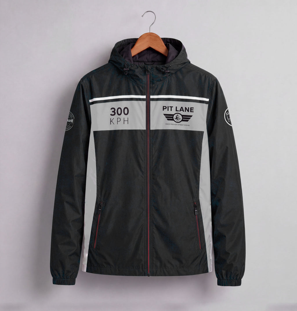 A black hooded windbreaker jacket with a gray chest panel and white racing-style graphics, hanging on a wooden hanger against a light gray wall. The chest reads '300 KPH' and 'PIT LANE CLOTHING' with a winged logo.