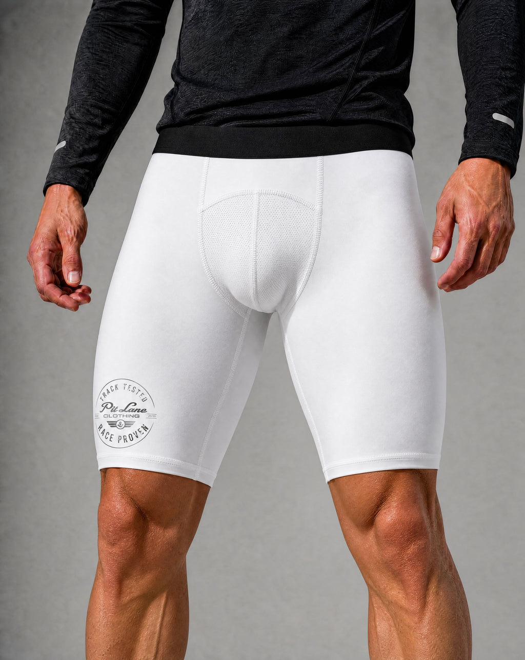 White compression cycling shorts with a padded seat and a circular 'PIT LANE CLOTHING' logo on the left leg, shown on a model wearing a black long-sleeve shirt against a gray studio background.