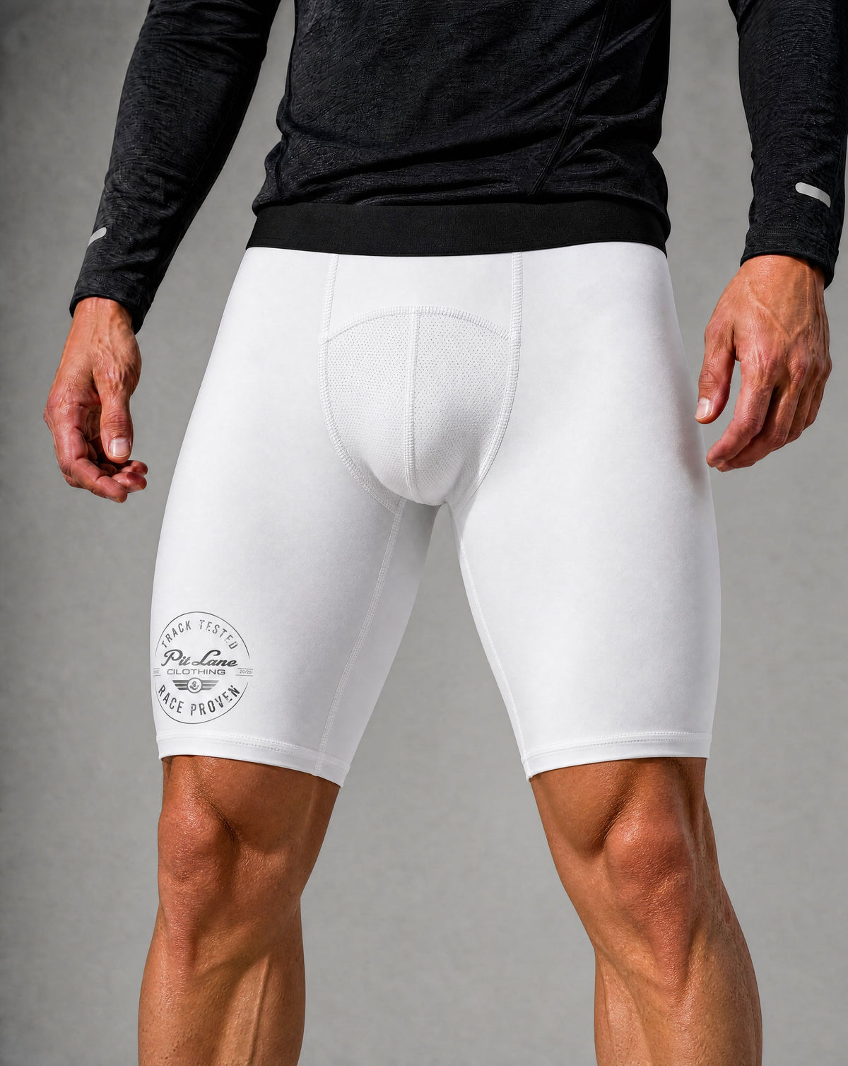 White compression cycling shorts with a padded seat and a circular 'PIT LANE CLOTHING' logo on the left leg, shown on a model wearing a black long-sleeve shirt against a gray studio background.
