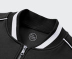 A navy blue zip-up jacket with white contrast stitching, ribbed collar, cuffs, and hem, hanging on a wooden hanger against a light gray textured wall. The left chest features a white circular logo reading 'KIT LANE CLOTHING' with a winged emblem.