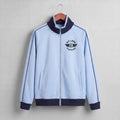 A close-up of a light blue zip-up jacket with a dark navy ribbed collar and a black 'PIT LANE CLOTHING' logo printed on the chest.