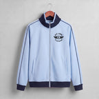 A close-up of a light blue zip-up jacket with a dark navy ribbed collar and a black 'PIT LANE CLOTHING' logo printed on the chest.