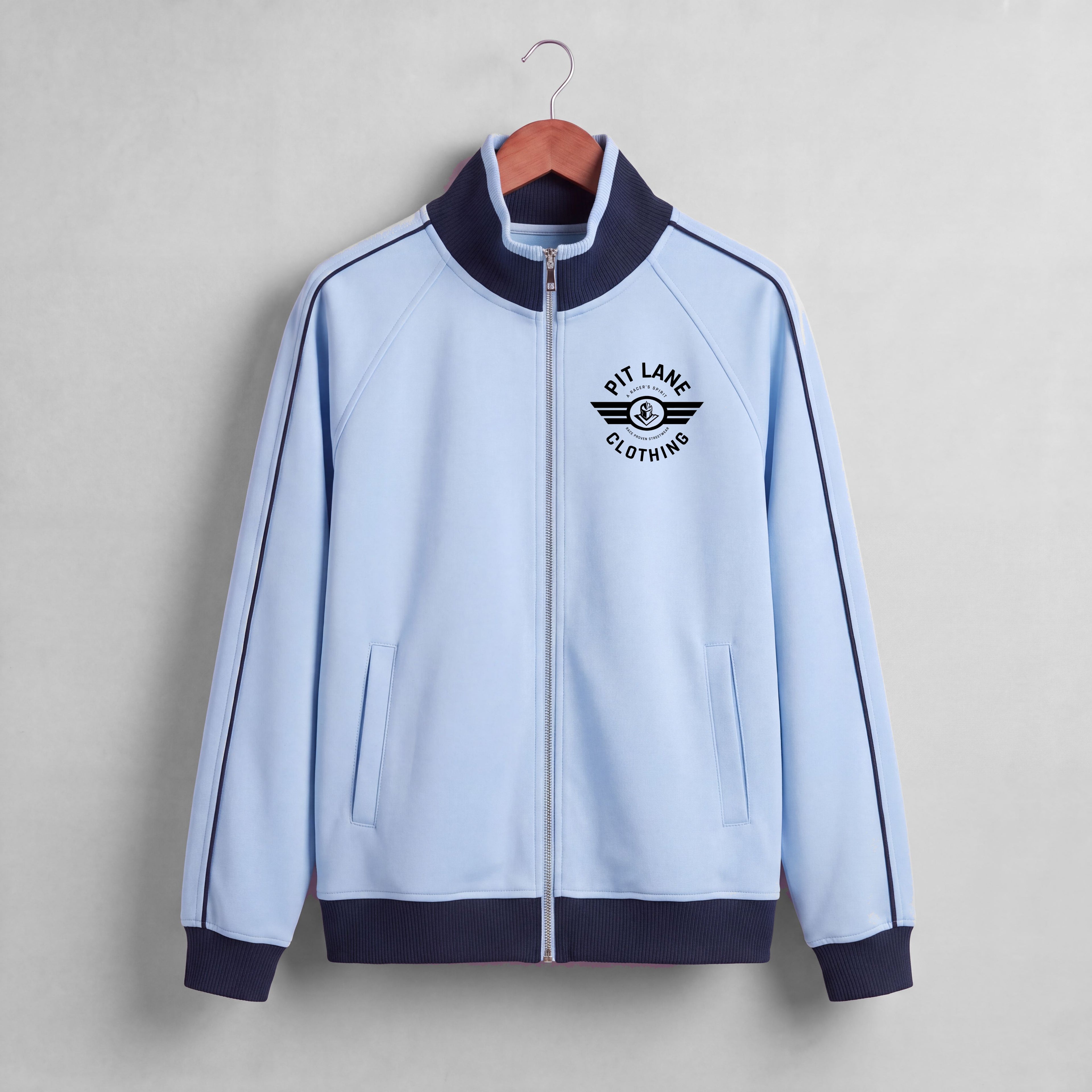A close-up of a light blue zip-up jacket with a dark navy ribbed collar and a black 'PIT LANE CLOTHING' logo printed on the chest.