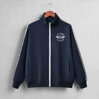 A navy blue zip-up track jacket with white shoulder stripes and a white chest logo reading 'PIT LANE CLOTHING', hanging on a wooden hanger against a light gray background.
