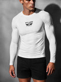 A man wearing a fitted white long-sleeve athletic shirt with a black 'PIT LANE' chest logo, paired with black shorts, photographed against a dark gray studio background.