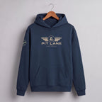A navy blue pullover hoodie hanging on a wooden hanger against a light gray wall. The hoodie features a gold-toned 'PIT LANE' winged logo on the chest and a small circular logo on the right sleeve.