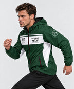 A man wearing a green and white PIT LANE CLOTHING windbreaker jacket, posed in a running stance against a light gray studio background.