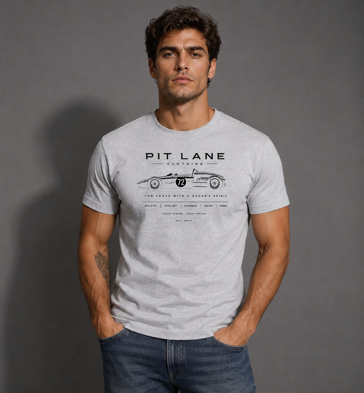 A man wearing a light gray heathered t-shirt with a black graphic print of a vintage race car and the text 'PIT LANE CLOTHING'.