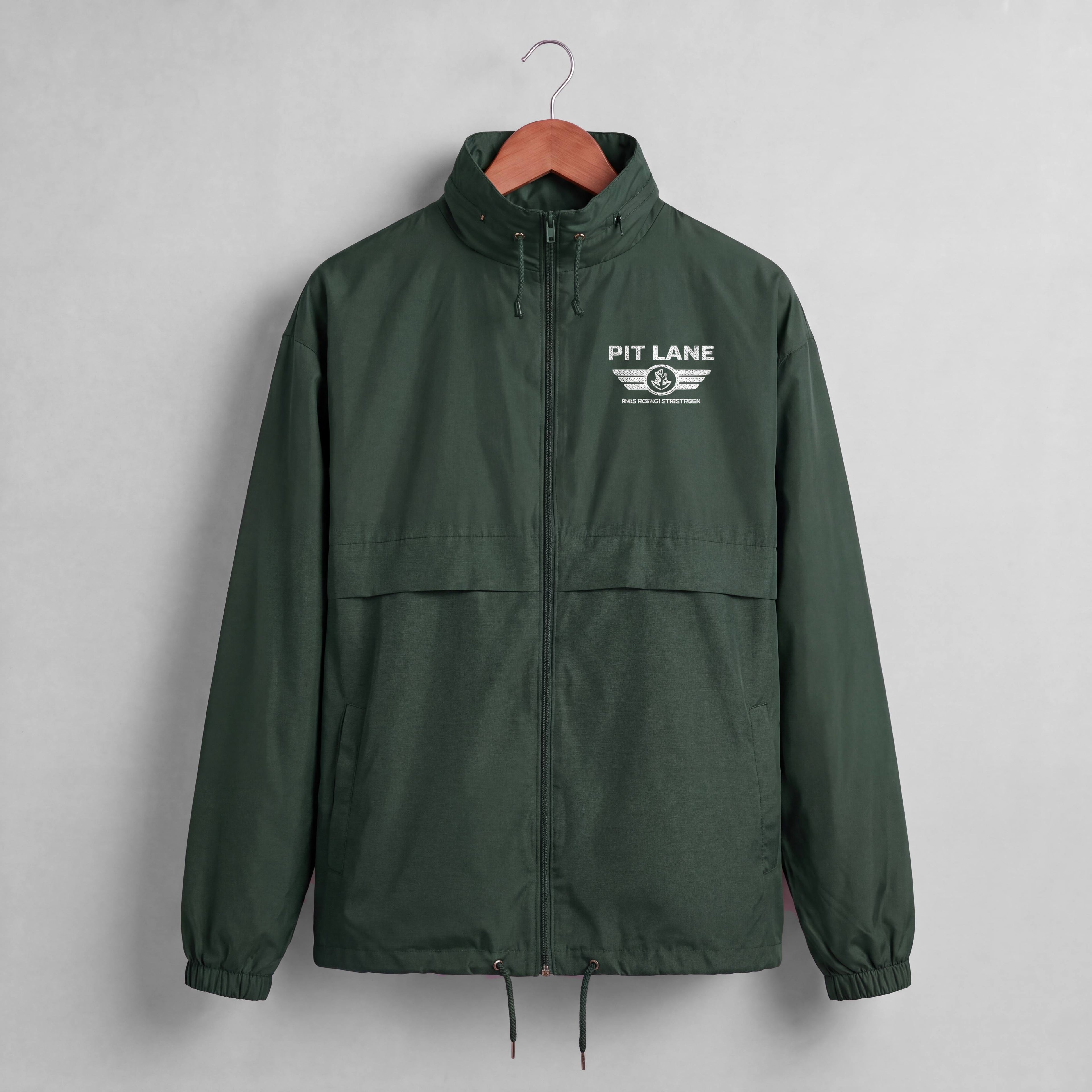 A dark green hooded windbreaker jacket hanging on a wooden hanger against a light gray wall. The jacket features a white 'PIT LANE' winged logo printed on the left chest.