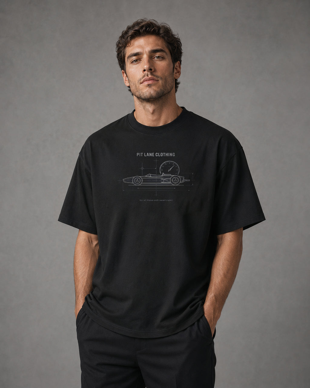 A black crewneck t-shirt hanging on a wooden hanger against a light gray wall. The shirt features a white blueprint-style graphic of a vintage race car with a speedometer, labeled 'PIT LANE CLOTHING' and 'for all those with racer's spirit'.