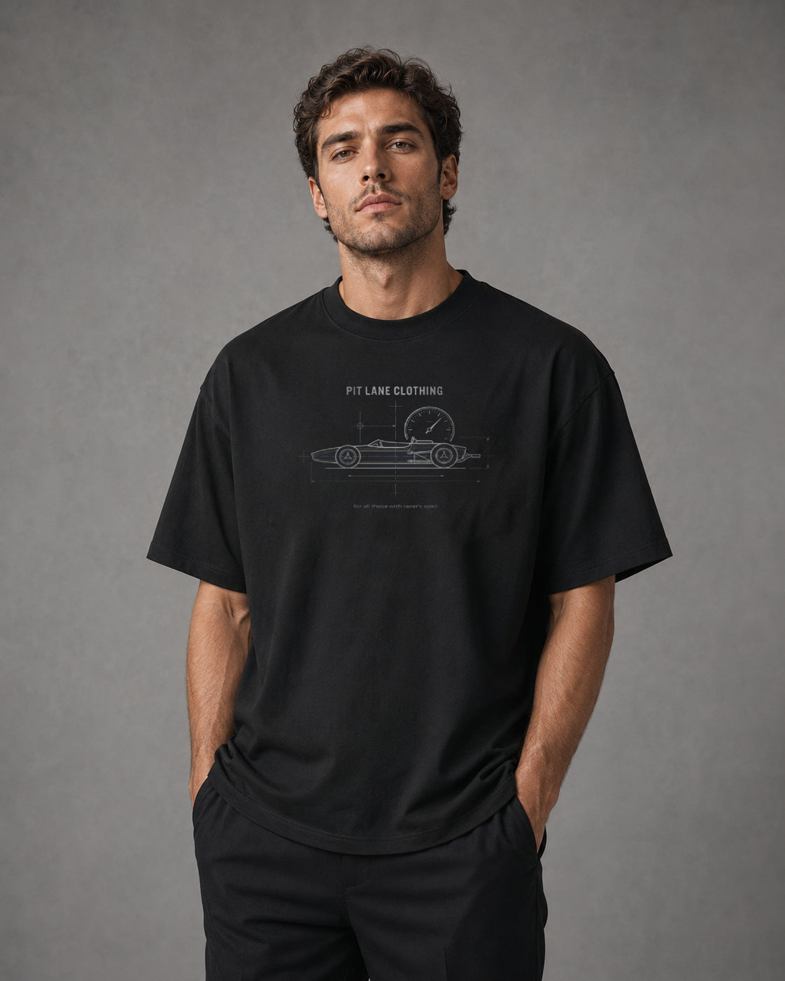 A black crewneck t-shirt hanging on a wooden hanger against a light gray wall. The shirt features a white blueprint-style graphic of a vintage race car with a speedometer, labeled 'PIT LANE CLOTHING' and 'for all those with racer's spirit'.