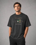A man wearing a dark charcoal gray graphic t-shirt with a vintage race car design and the text 'PIT LANE CLOTHING' and 'CHICANE'.