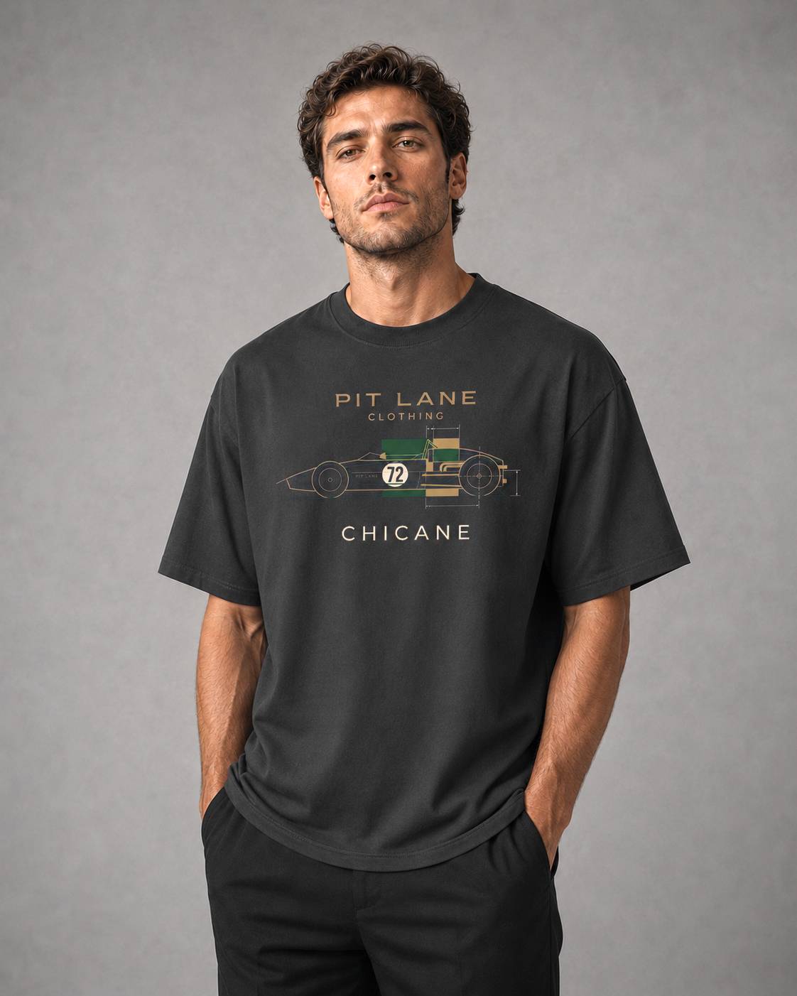 A man wearing a dark charcoal gray graphic t-shirt with a vintage race car design and the text 'PIT LANE CLOTHING' and 'CHICANE'.