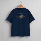 A navy blue crewneck t-shirt hanging on a wooden hanger against a light gray wall. The shirt features a graphic of a vintage race car with dimensions and the text 'PIT LANE CLOTHING', 'CHICANE', and the number '72' in gold, green, and white.