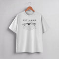 A light gray heather crewneck t-shirt hanging on a wooden hanger against a neutral gray background. The shirt features a black graphic print of a vintage race car with the text 'PIT LANE CLOTHING' and 'FOR FANS WITH A RACER'S SPIRIT'.