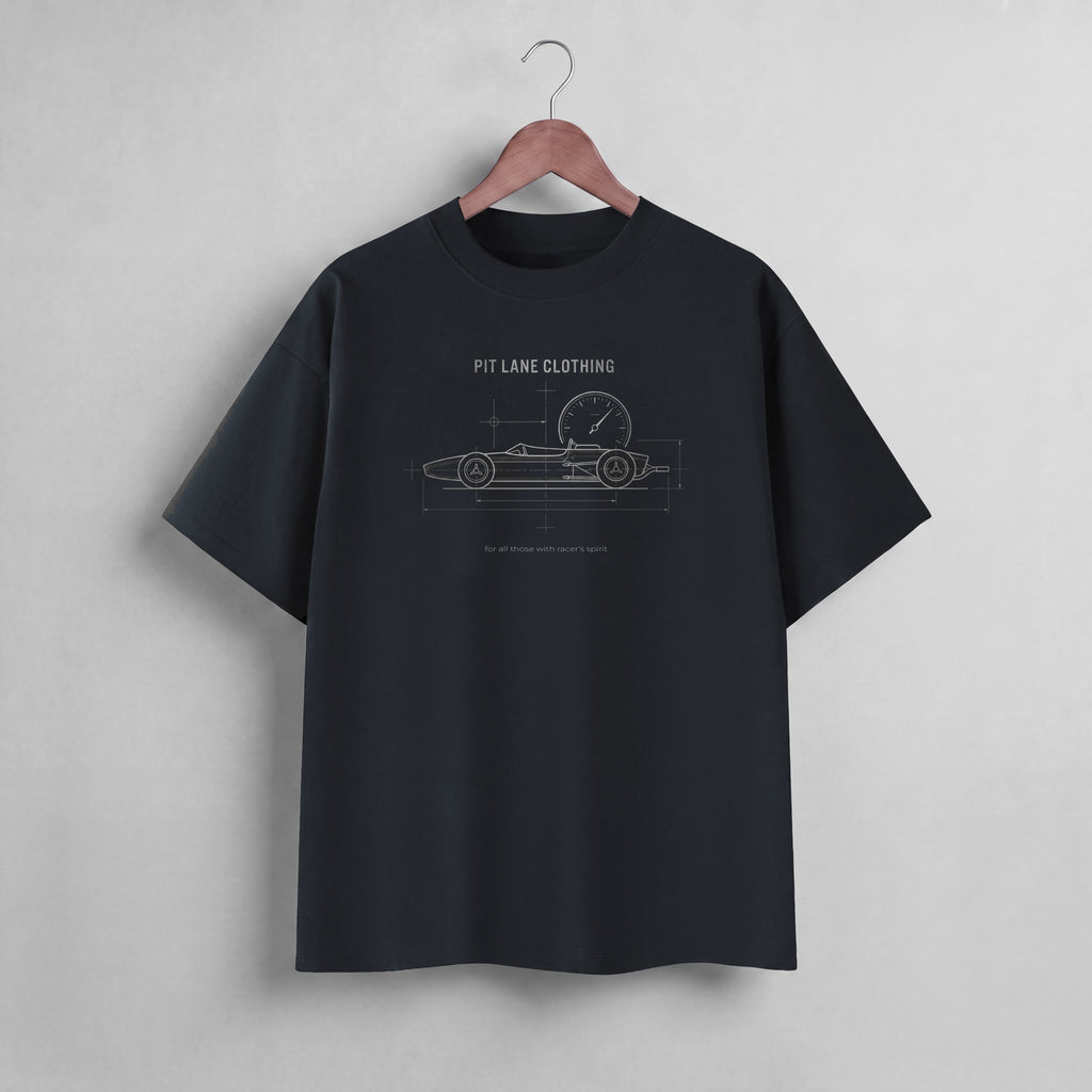 A black short-sleeve t-shirt hanging on a wooden hanger against a light gray wall. The shirt features a white line-art graphic of a race car with a clock and the text 'PIT LANE CLOTHING' printed on the chest.