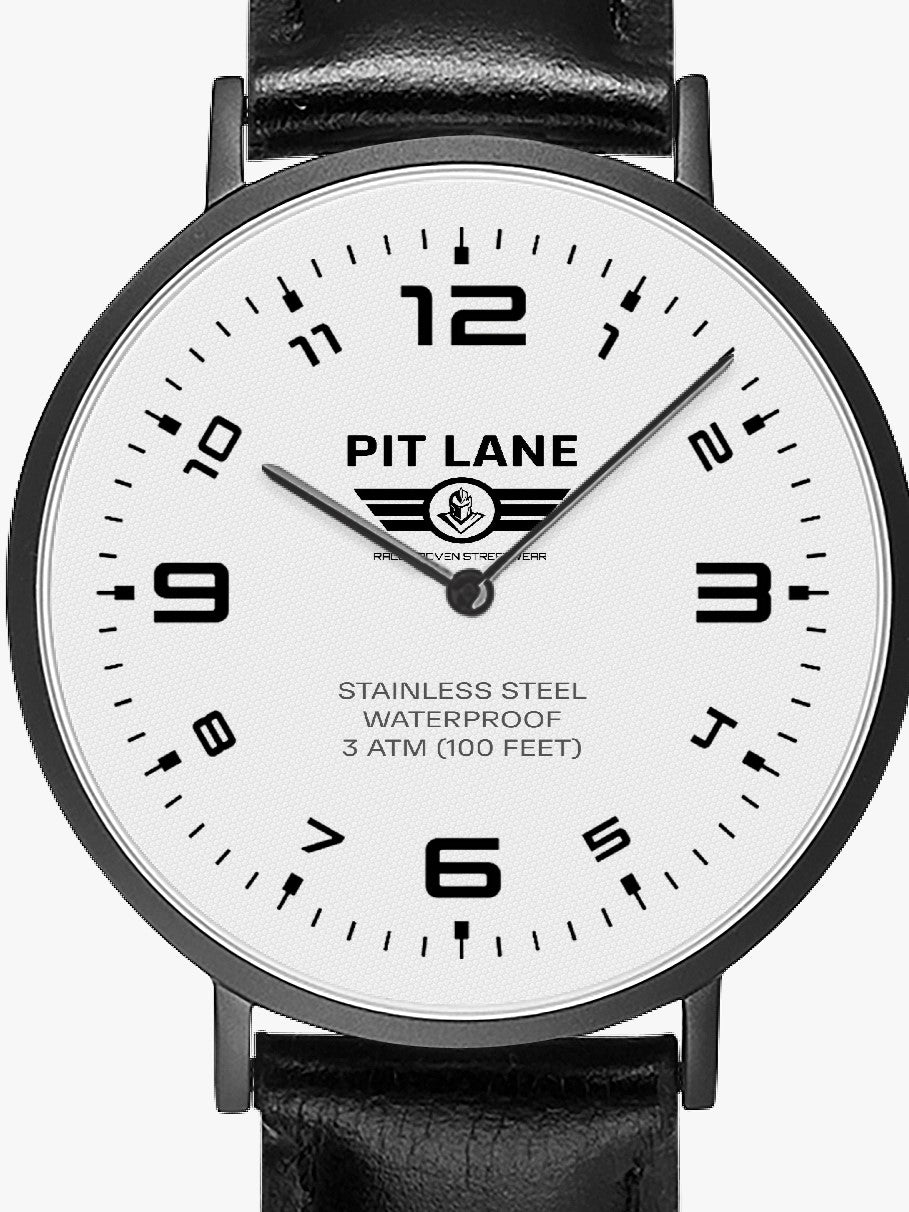 A Pit Lane wristwatch with a black leather strap, black case, and a white dial with black Arabic numerals, shown against a light gray background.