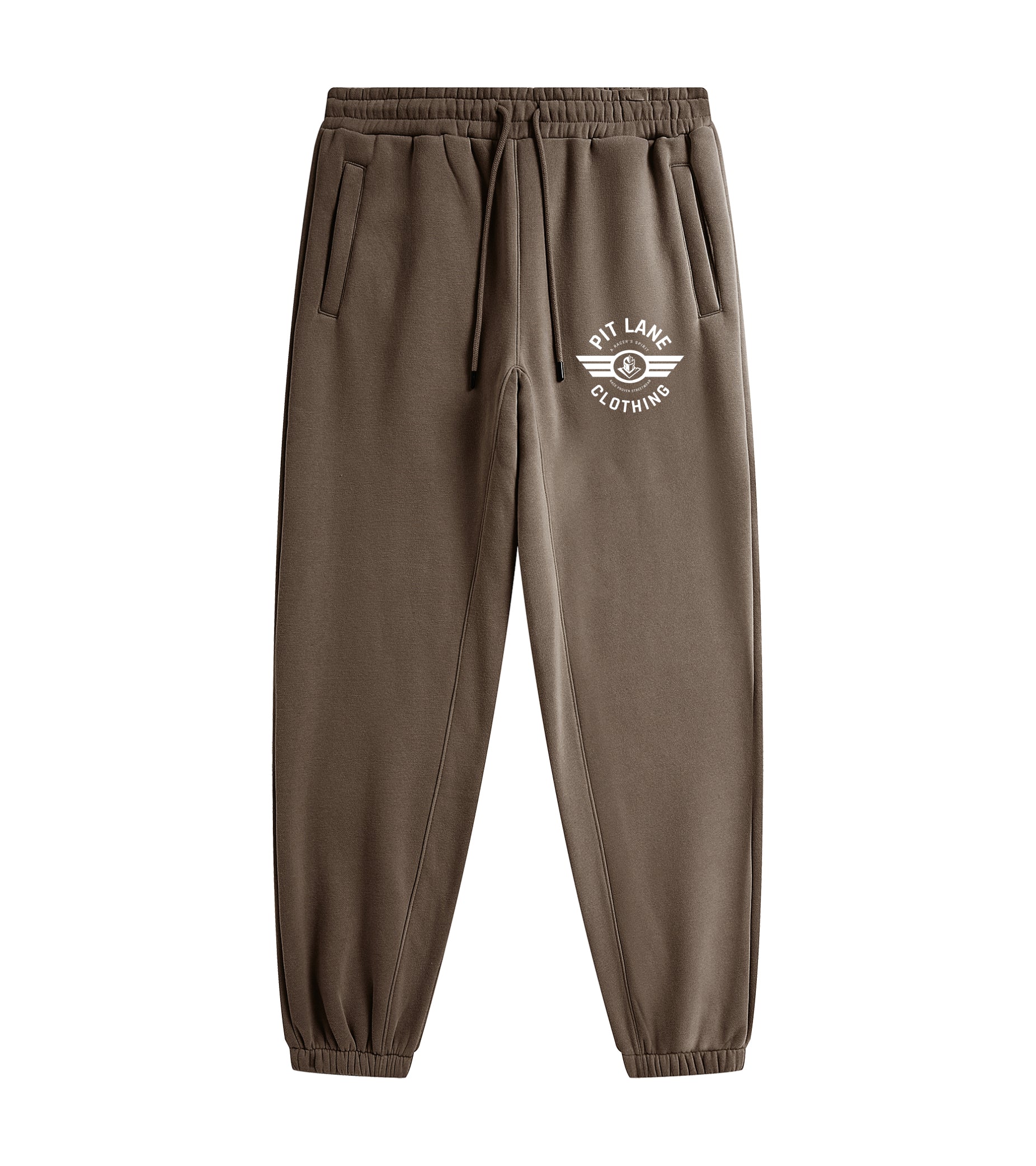 A person wearing brown jogger sweatpants with a white circular chest logo that reads 'PIT LANE CLOTHING' and white sneakers, photographed against a clean light gray studio background.