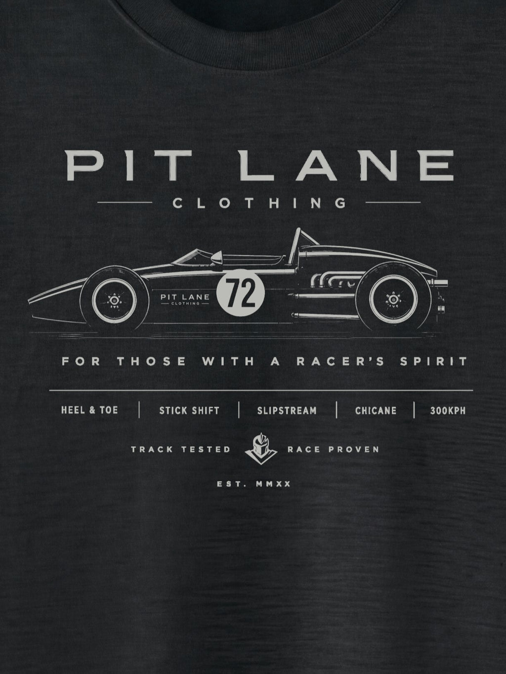 A close-up of a black t-shirt featuring a white graphic print of a vintage race car with the number 72 and the text 'PIT LANE CLOTHING' and 'FOR THOSE WITH A RACER'S SPIRIT'.
