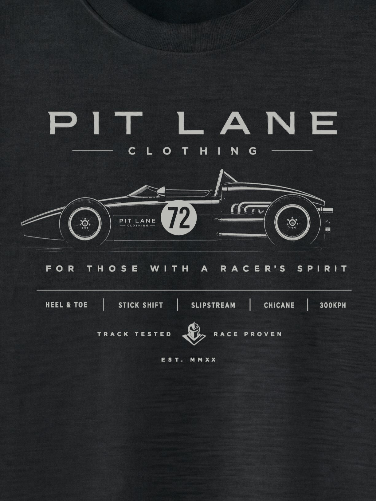 A close-up of a black t-shirt featuring a white graphic print of a vintage race car with the number 72 and the text 'PIT LANE CLOTHING' and 'FOR THOSE WITH A RACER'S SPIRIT'.