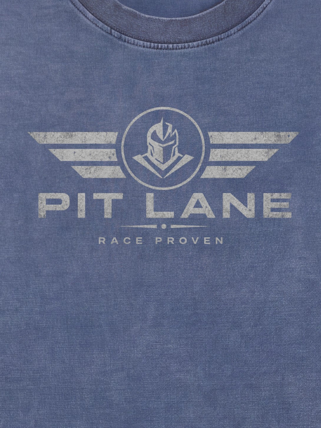 Close-up of a heathered blue crewneck t-shirt featuring a distressed white graphic print of a helmeted knight inside a circle with wings, and the text 'PIT LANE' and 'RACE PROVEN'.