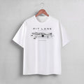 A white short-sleeve crewneck t-shirt hanging on a wooden hanger against a light gray wall. The shirt features a black graphic print of a race car with the text 'PIT LANE CLOTHING' and 'SLIPSTREAM' on the chest.