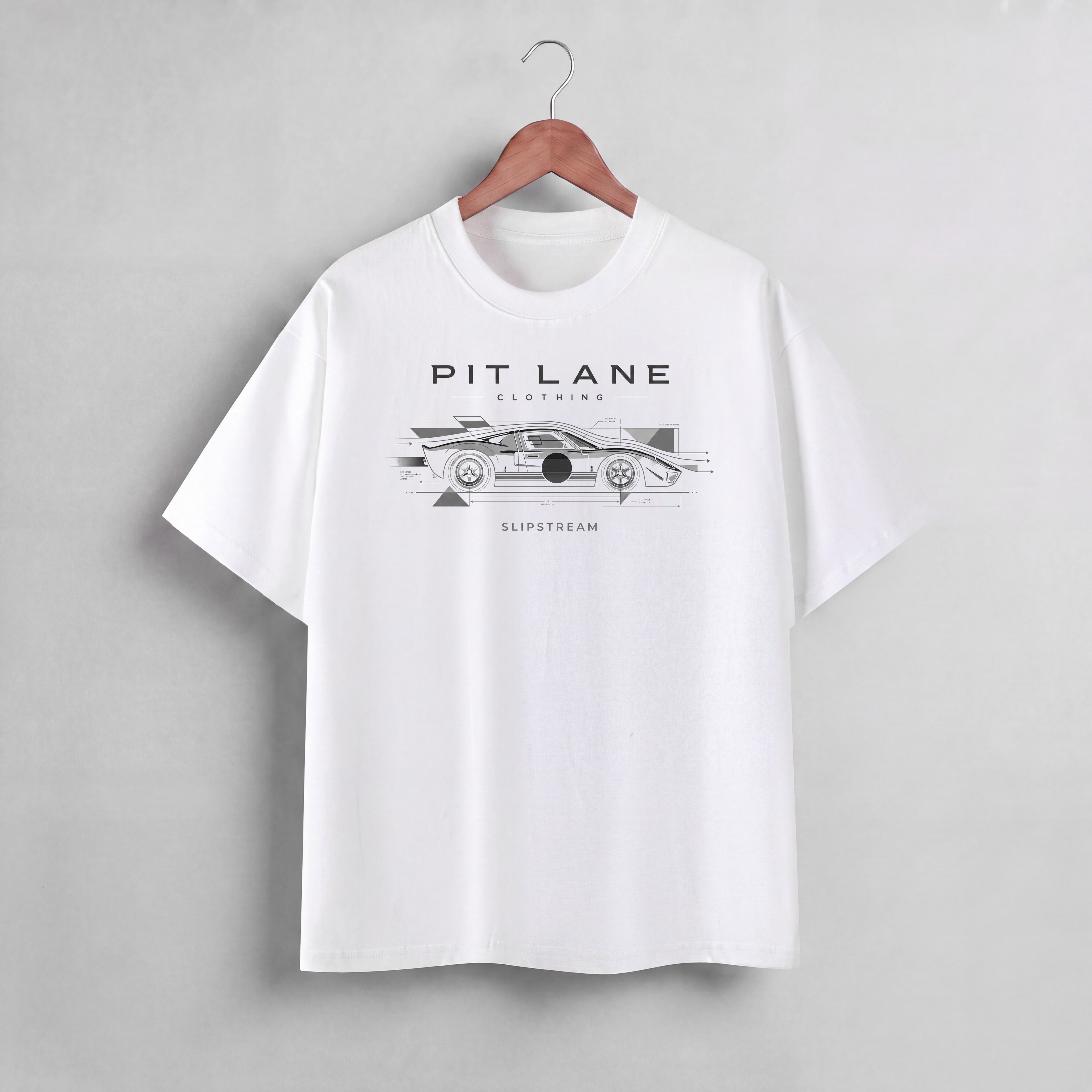 A white short-sleeve crewneck t-shirt hanging on a wooden hanger against a light gray wall. The shirt features a black graphic print of a race car with the text 'PIT LANE CLOTHING' and 'SLIPSTREAM' on the chest.
